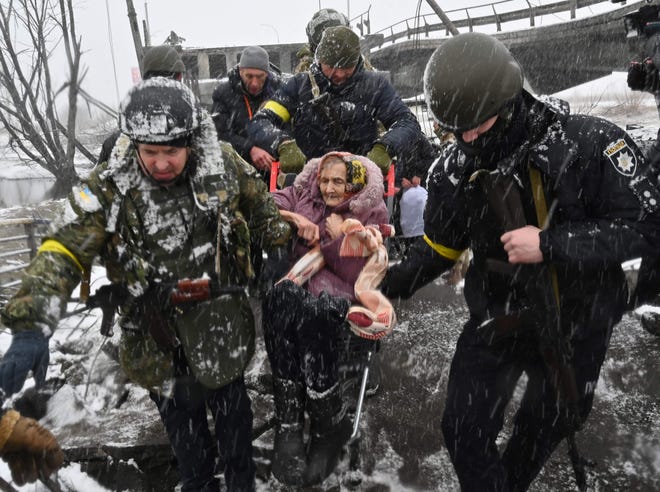 Soldados ucranianos ayudan a una anciana a cruzar un puente destruido durante la evacuación de la ciudad de Irbin, al noroeste de Kiev, el 8 de marzo de 2022.