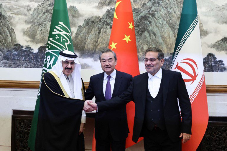 El chino Wang Yi, el iraní Ali Shamkhani y el saudita Musaed bin Mohammed Al-Aiban toman fotografías durante una reunión en Beijing, China, el 10 de marzo de 2023.
