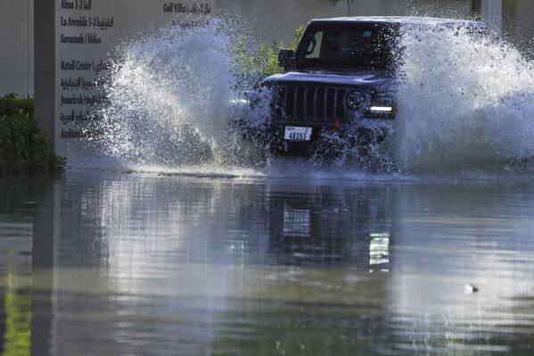 Una camioneta conduce a través de las inundaciones que cubren una carretera en Dubai, Emiratos Árabes Unidos, el miércoles 17 de abril de 2024. Fuertes tormentas eléctricas azotaron los Emiratos Árabes Unidos el martes, arrojando más de un año y medio de lluvia sobre la ciudad desértica de Dubai.  En cuestión de horas, partes de las principales carreteras y su aeropuerto internacional quedaron sumergidas.  (Foto AP/Jon Gambrell)